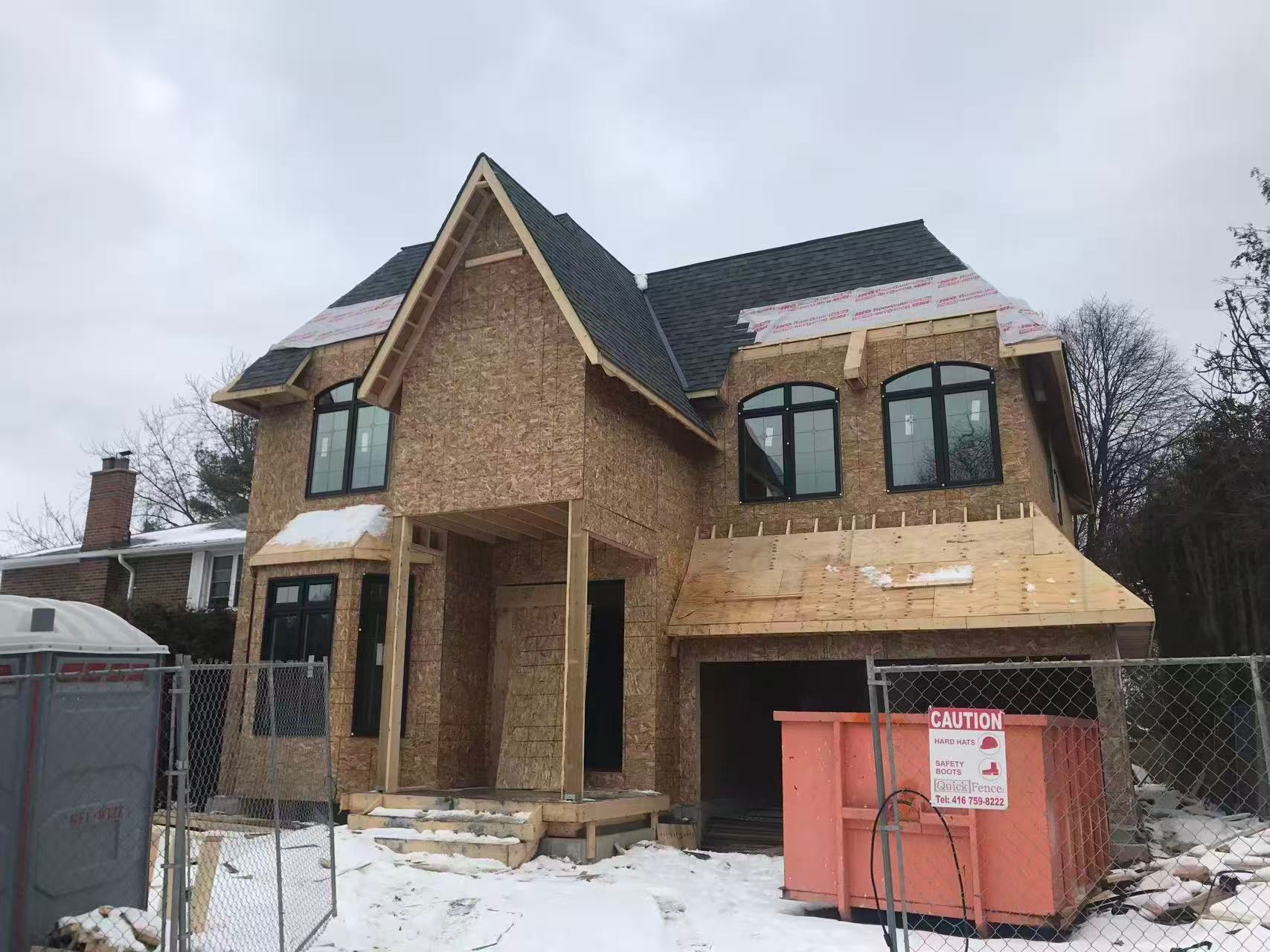 Exterior of a new construction home with sheathing visible and dumpster on site